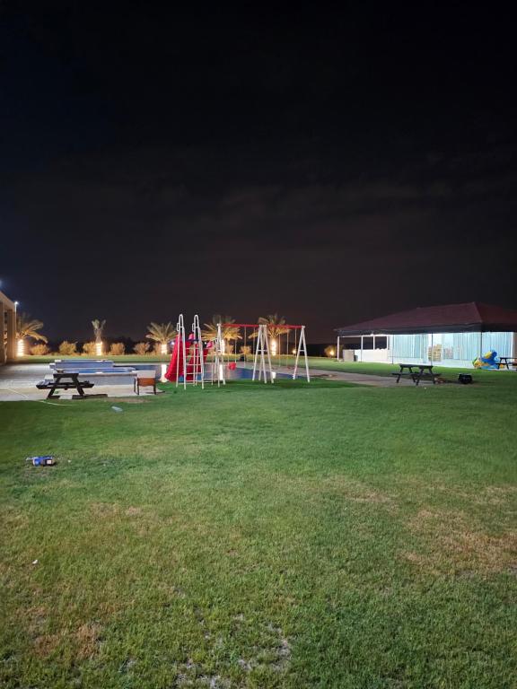 a park with benches and a playground at night at مزرعة الاسترخاء in Umm Al Quwain