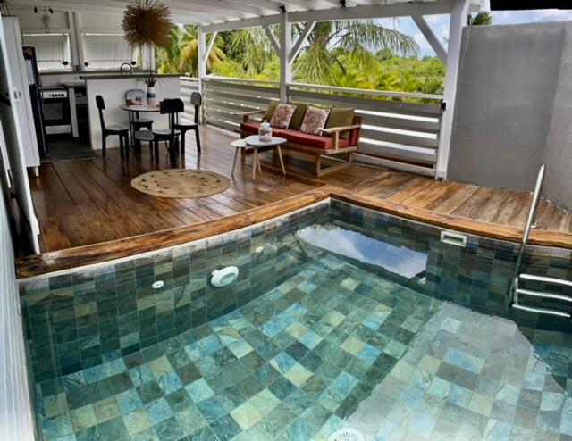 a swimming pool with a table and a living room at Villa papyrus in Saint-François