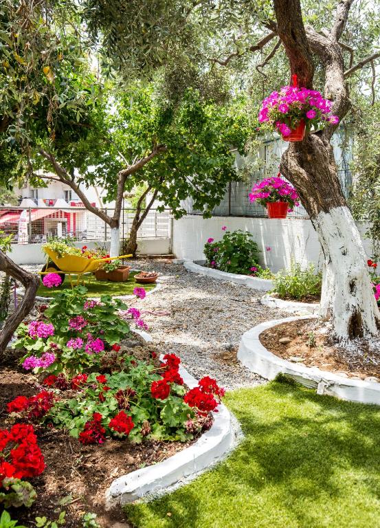 a garden with red and pink flowers and a tree at Ianos Apartments in Potos