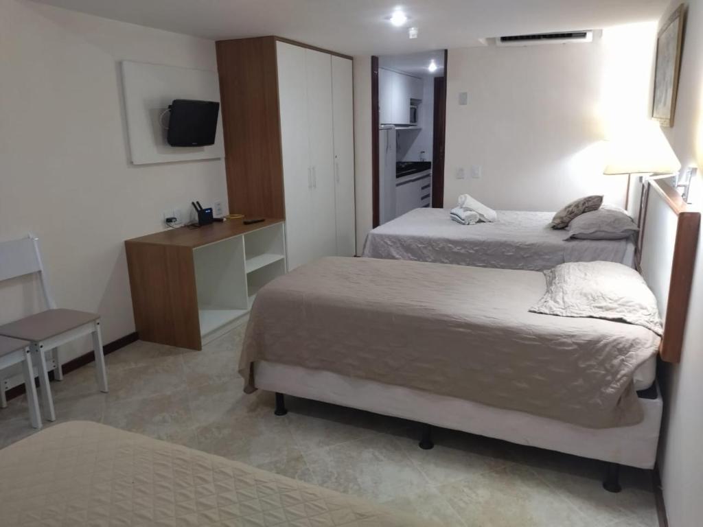 Habitación de hotel con 2 camas y escritorio en Victoria Marina Flat 2203 en Salvador