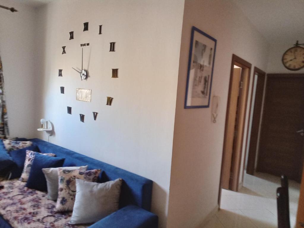 Sofá azul en la sala de estar con reloj en la pared en Appartement calme au centre en Oujda