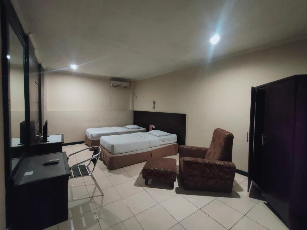 a bedroom with two beds and a tv and a chair at Hotel Syariah Taman Cibinong 2 By FPH 