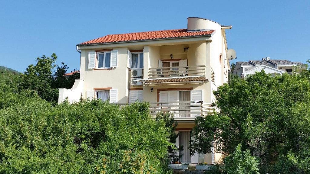 a building on a hill with trees in the foreground at Apartments Kristina in Klenovica