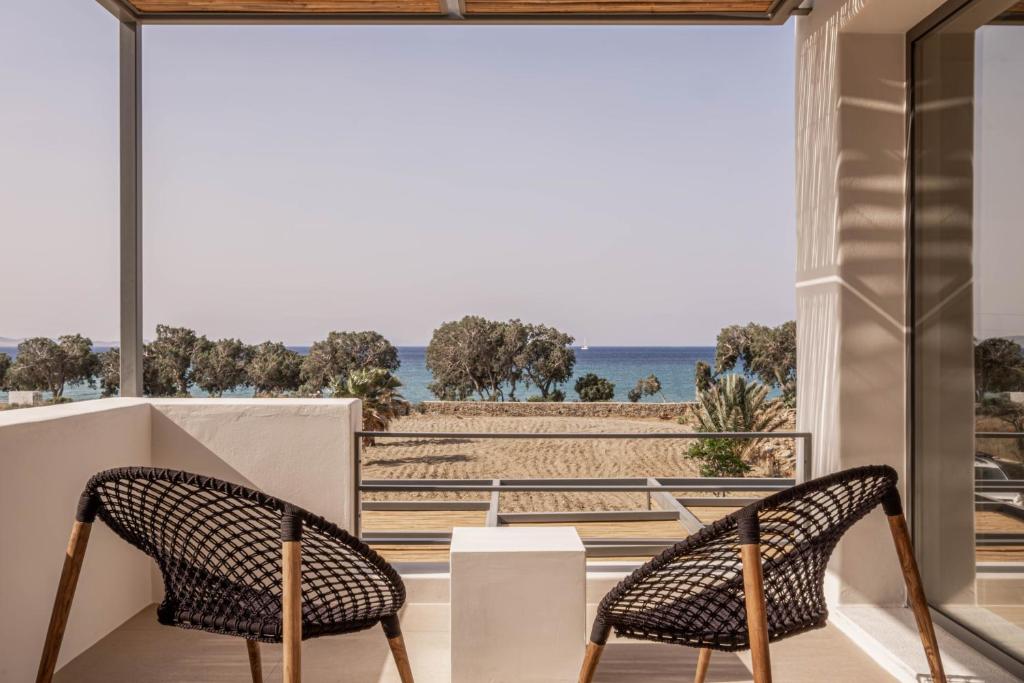 two chairs on a balcony with a view of the beach at Yenesis Seaside Retreat - Adults only in Tinos Town