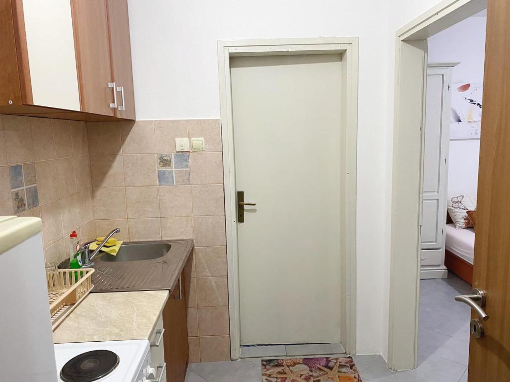 a small kitchen with a door to a sink at Pejovic Guest House in Sutomore