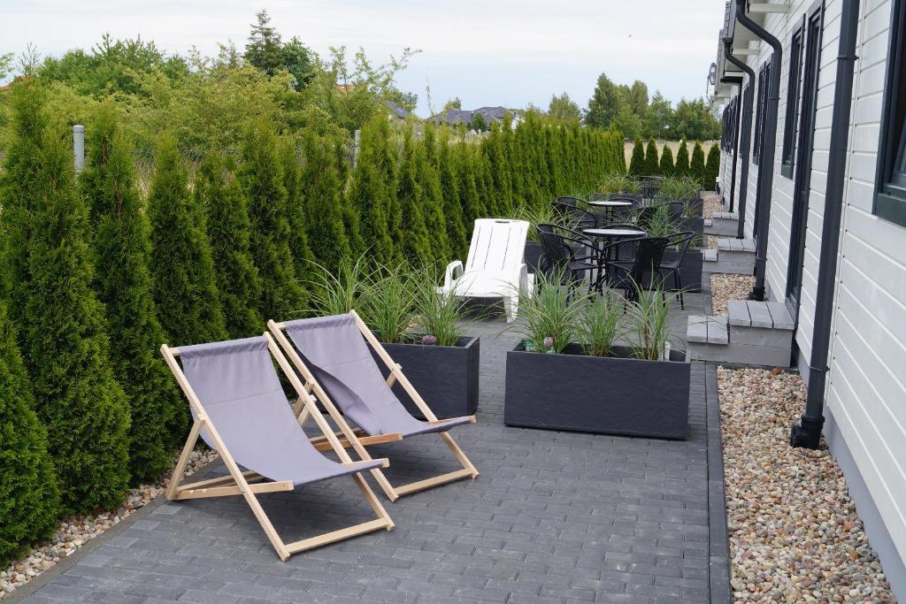 2 chaises longues assises sur une terrasse agrémentée de plantes dans l'établissement SŁONECZNE DOMKI, à Gąski