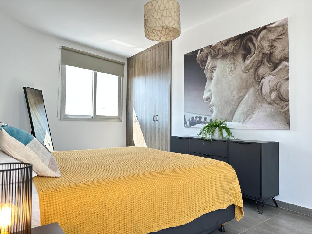 a bedroom with a yellow bed with a painting on the wall at Vacation mode Apartment in Ayia Napa