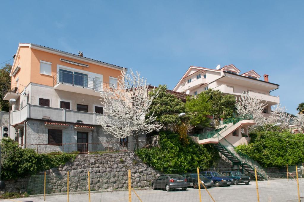 a building on a hill with cars parked in a parking lot at Apartments Komel in Opatija