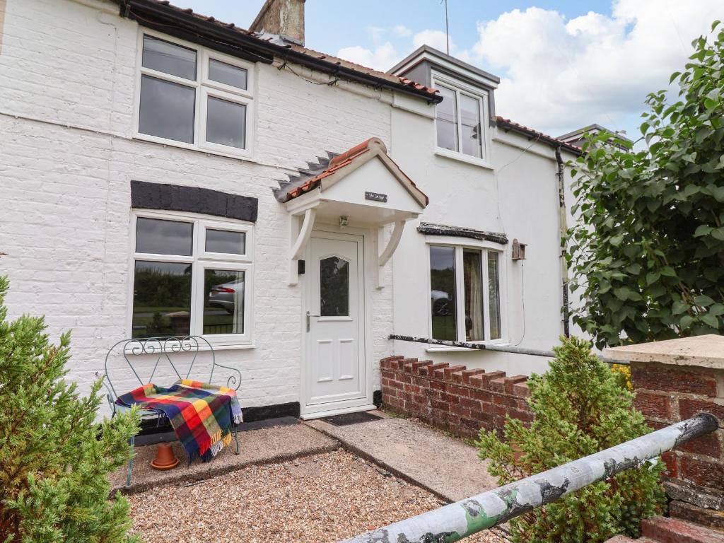 a white house with a bench in front of it at The Cottage in Great Driffield