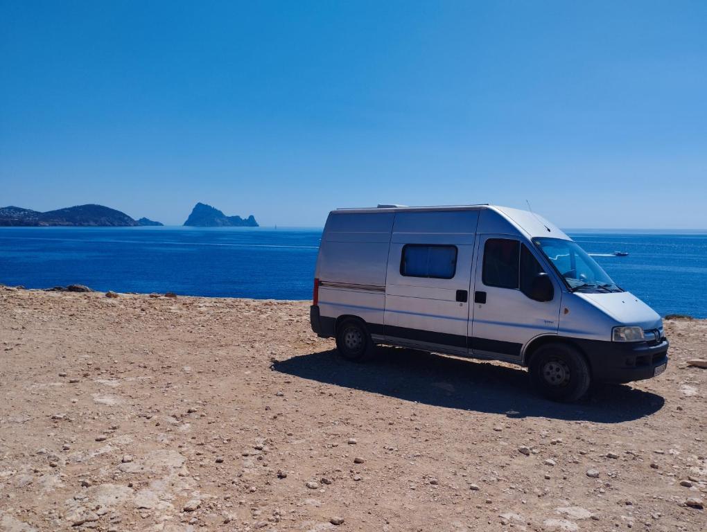 a white van parked on a beach near the water at Casa movil in Santa Gertrudis de Fruitera