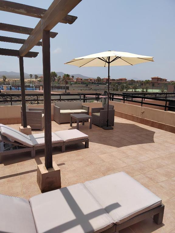 a patio with benches and an umbrella on a roof at Adam Home Origo Mare in Lajares