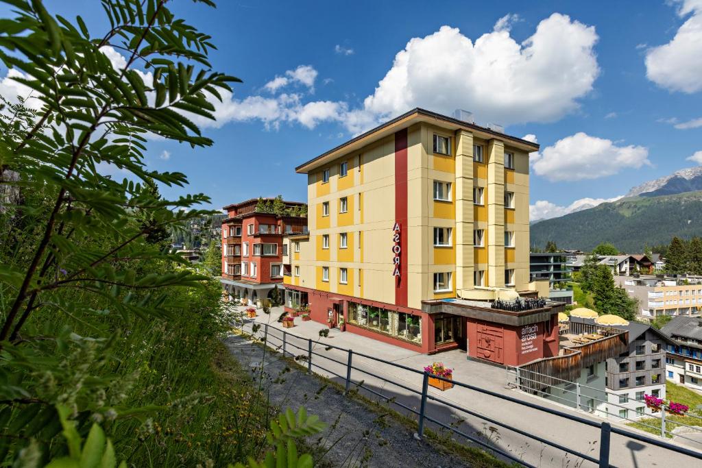 a yellow and red building in a city at Pension Arosa - Self Check-In in Arosa