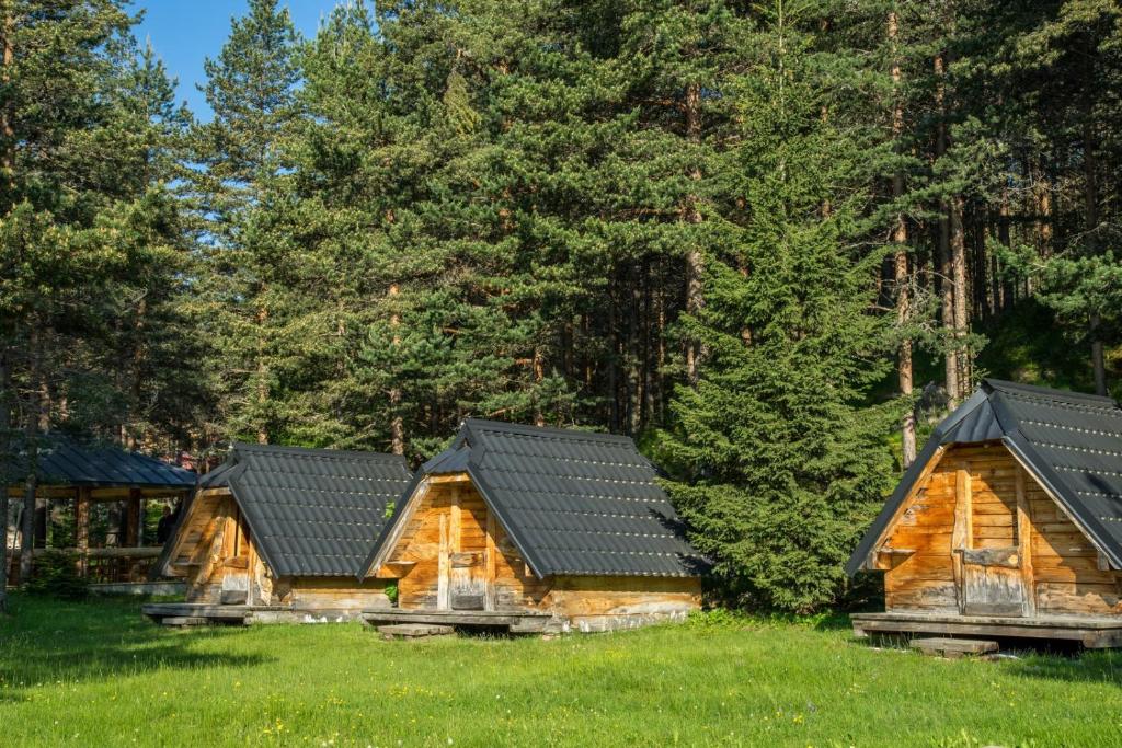 eine Blockhütte auf einem Feld mit Bäumen in der Unterkunft Eco Camp Chalets pod Gorom in Žabljak