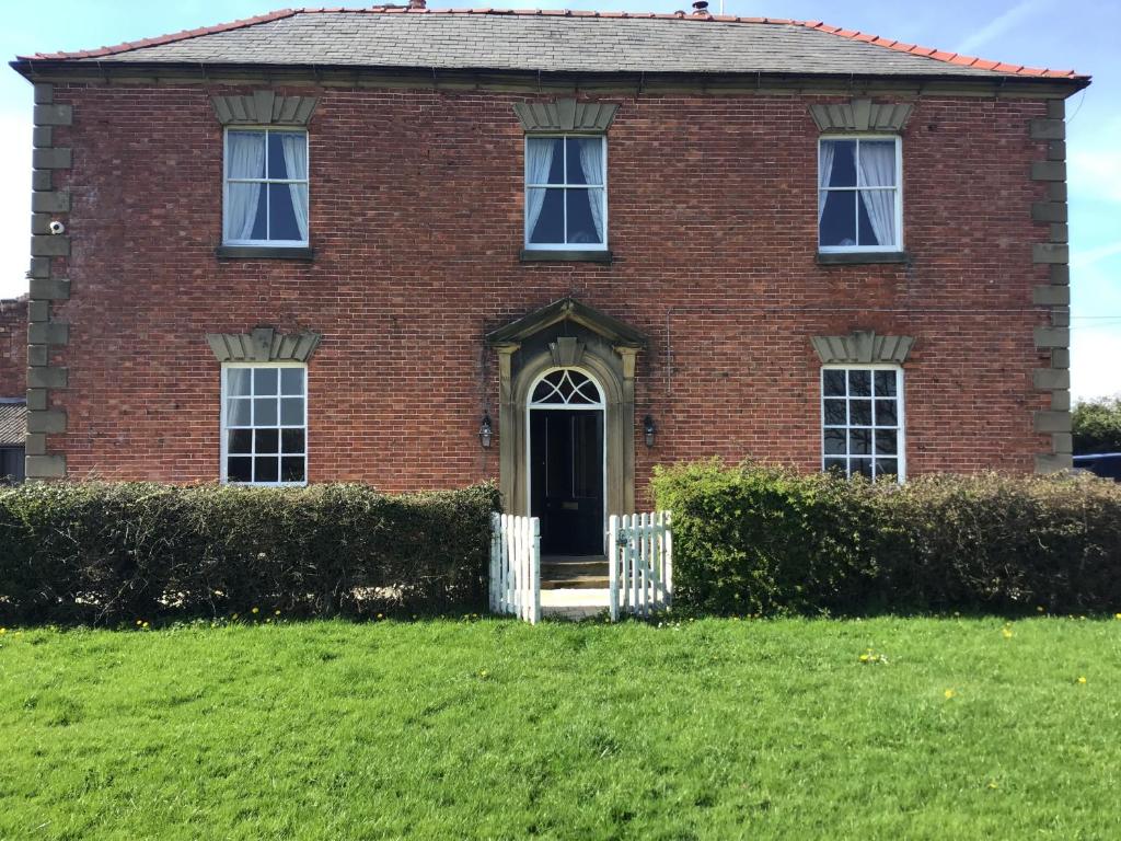 an old brick house with a green lawn at Plas Bostock Farm in Wrexham