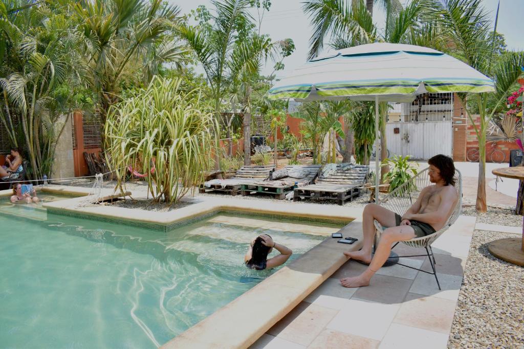 a woman sitting in a chair next to a swimming pool at Nopalero Hostel in Puerto Escondido