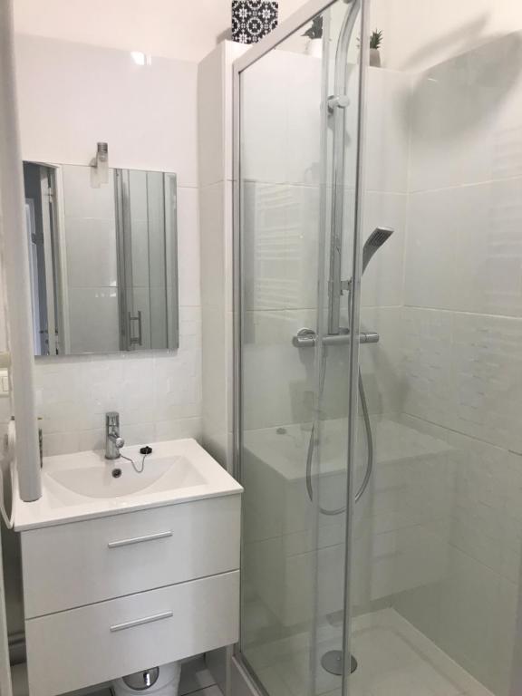 uma casa de banho branca com um chuveiro e um lavatório. em Neuville secrete em Dieppe