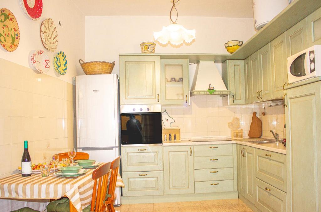 a kitchen with a table and a white refrigerator at A Casa di Ale in Sorso