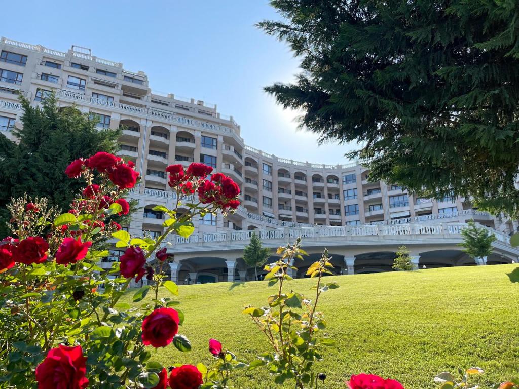 een groot gebouw met rode bloemen ervoor bij Cabacum Beach Residence AP.20 in Varna