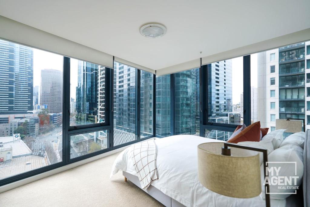 - une chambre dotée de grandes fenêtres et d'un lit avec un grand couvre-lit blanc dans l'établissement Luxury Living at Its Finest, à Melbourne