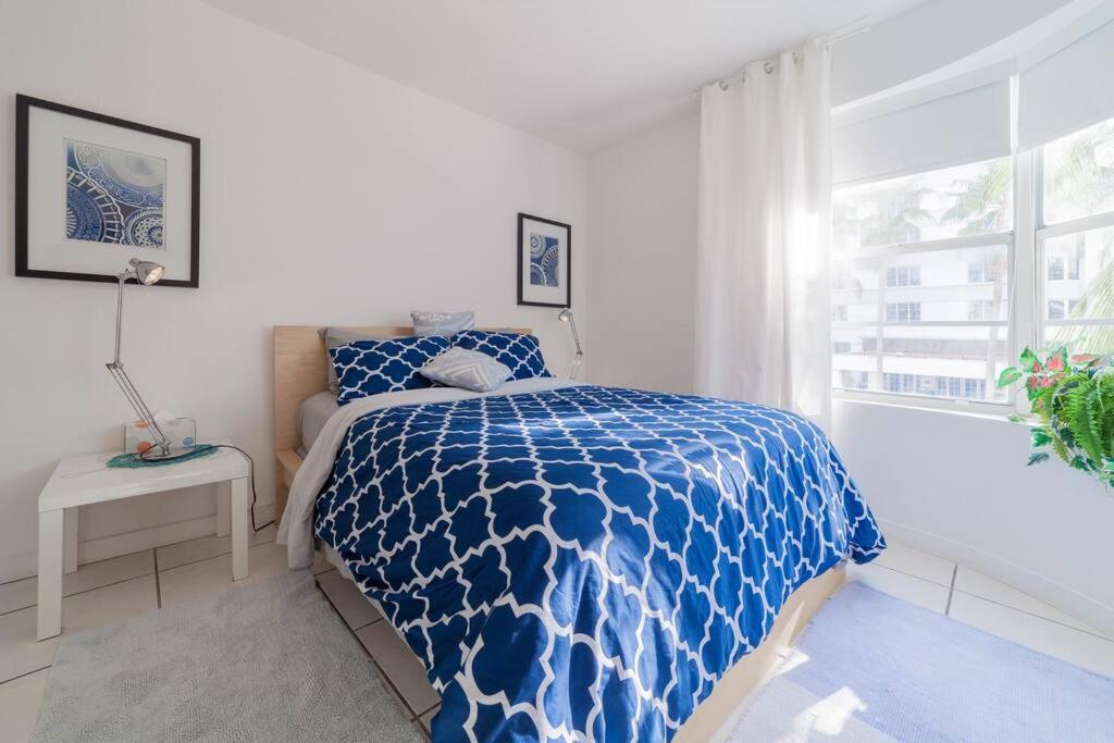 a bedroom with a blue and white bed and a window at BEACH VIBES in Miami Beach