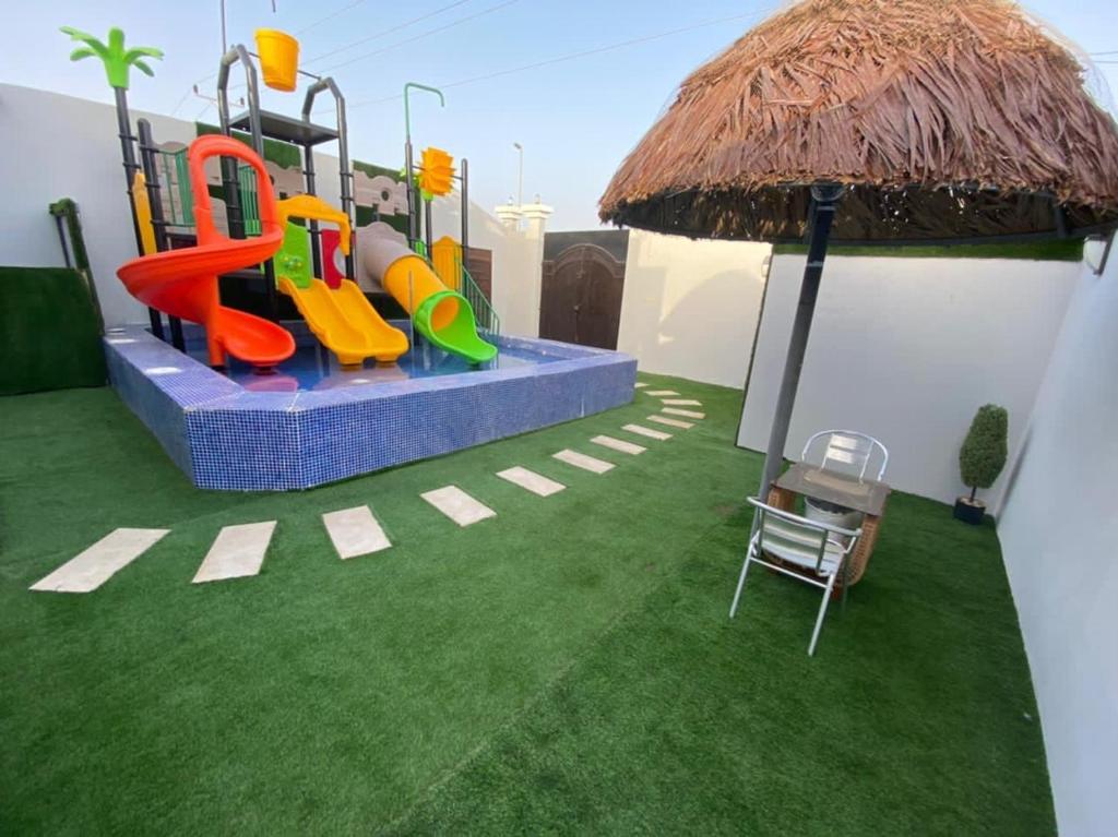 a playground with a slide and an umbrella at استراحة الملكة بالرايس in Rayyis