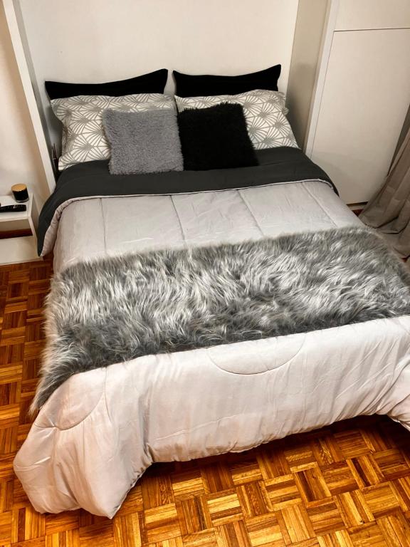 Una cama con una manta gris encima. en Esme en Buenos Aires