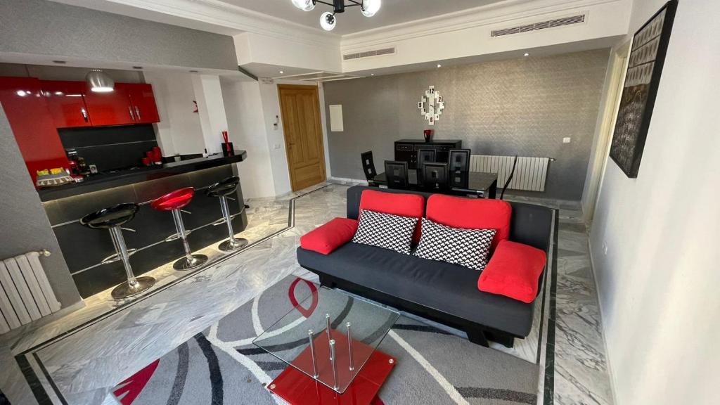 soggiorno con divano nero e cuscini rossi di Appartement en bord de mer a Monastir