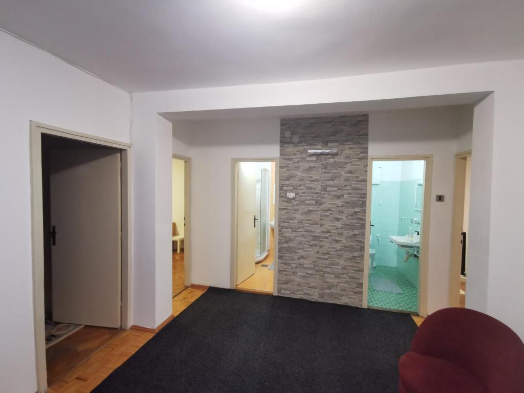 a living room with a stone wall and a bathroom at Apartman Monaco in Kraljevo
