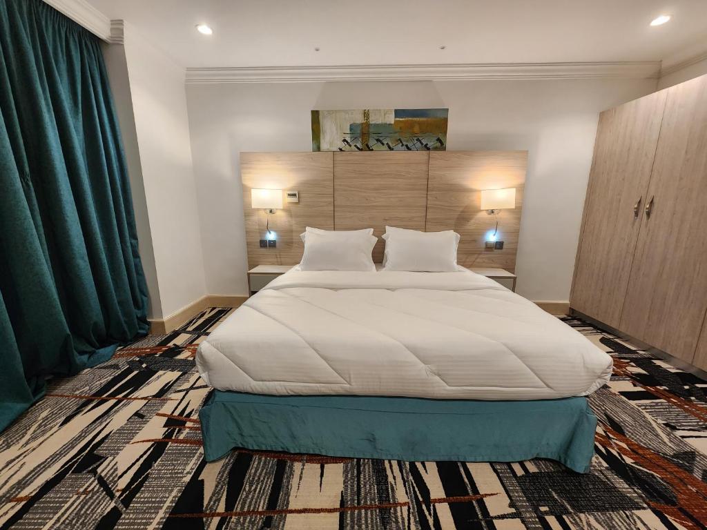 sypialnia z dużym białym łóżkiem z zielonymi zasłonami w obiekcie Helnan Royal w Dubaju
