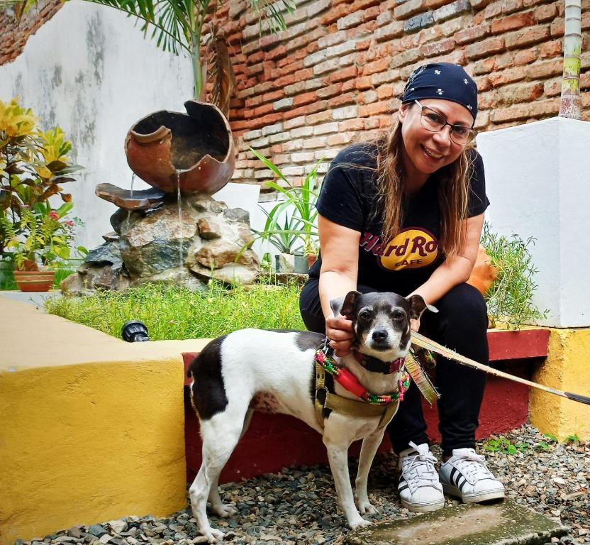 a woman sitting next to a small dog on a leash at Albarrada Hotel Boutique in Mompós