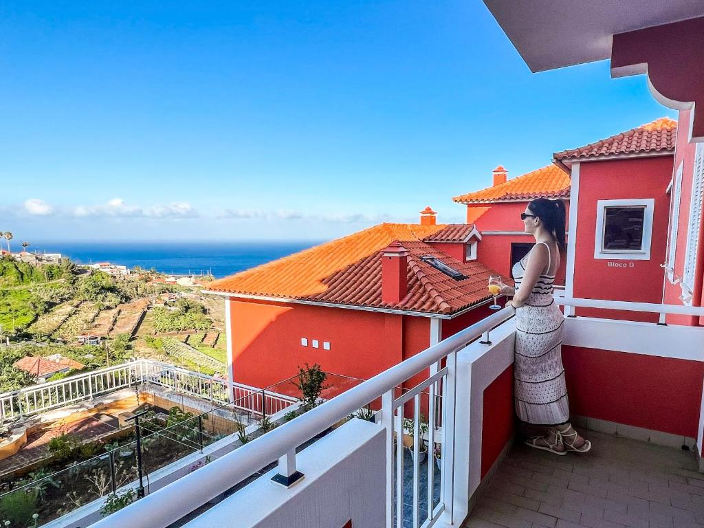 a woman standing on a balcony looking out at the ocean at The Pink Villa in Caniço
