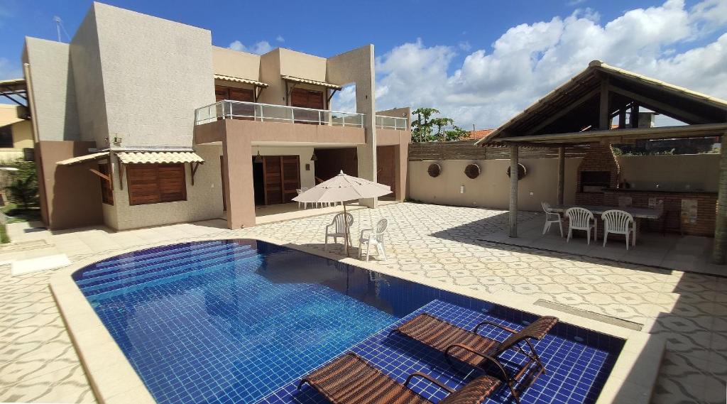 a swimming pool with chairs and a house at Casa Janga Mar in Barra de São Miguel