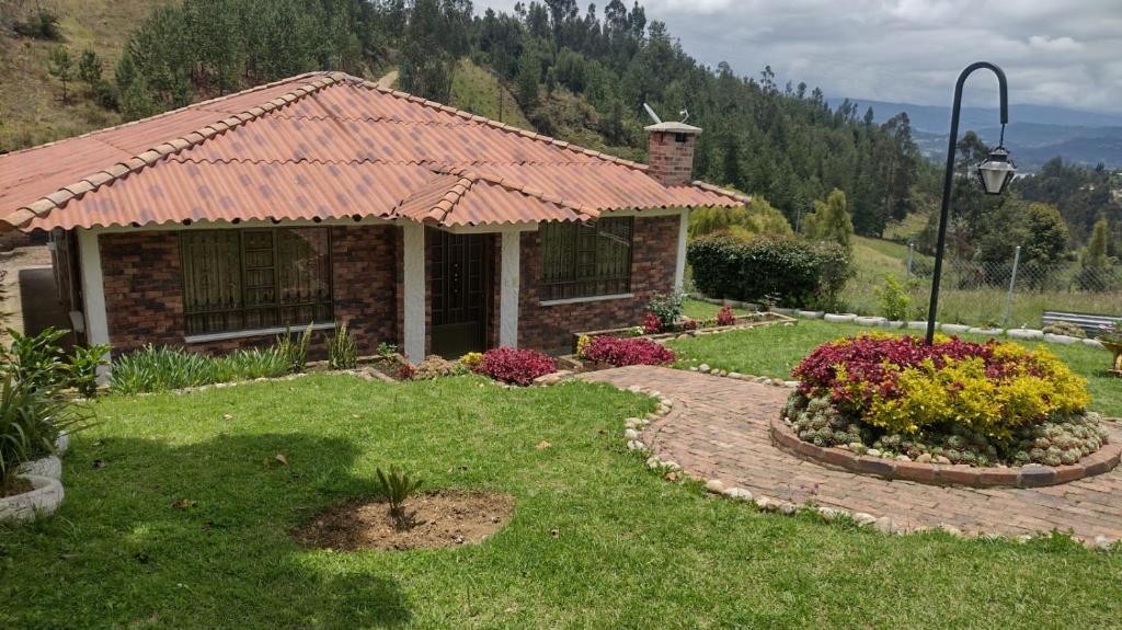 a house with a garden with flowers in front of it at Cabaña Villa Gabriela in Paipa