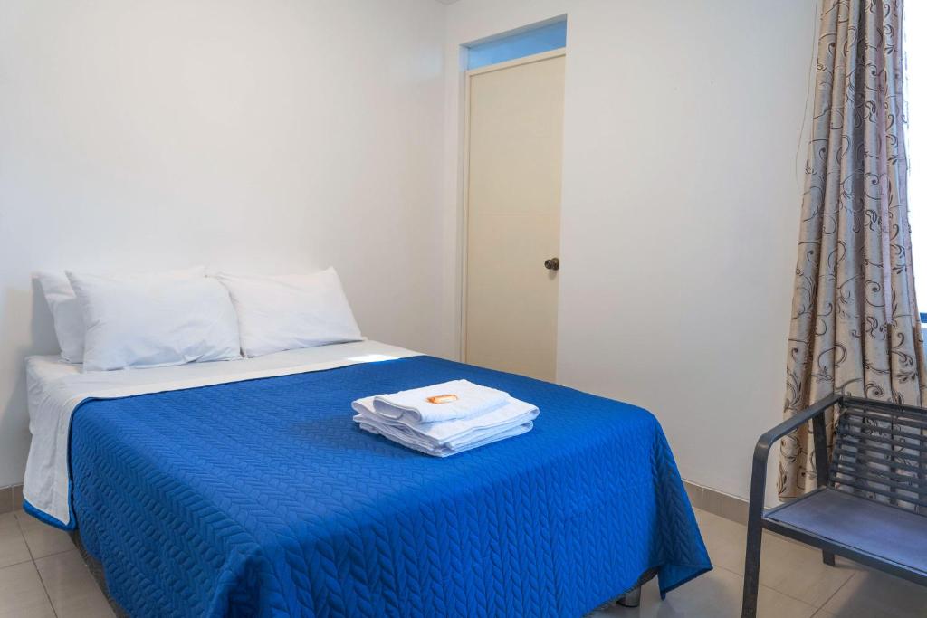 a room with a bed with a blue blanket at SGH Paracas Hospedaje in Paracas