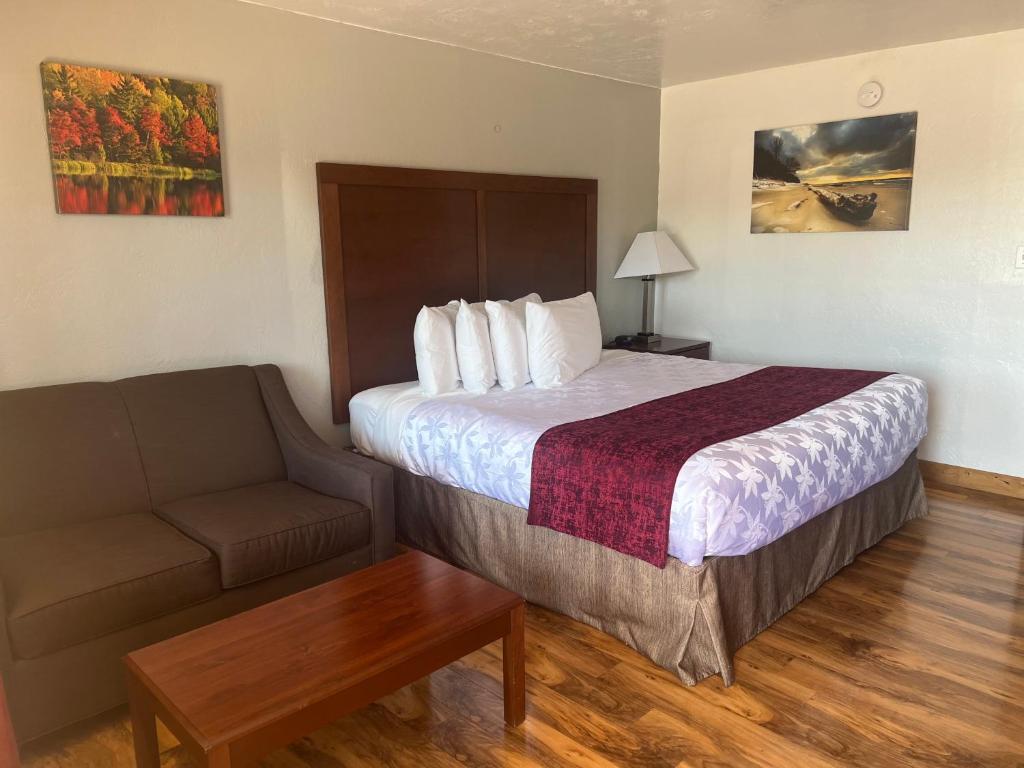 a hotel room with a bed and a couch at Red Carpet Inn Medford in Medford