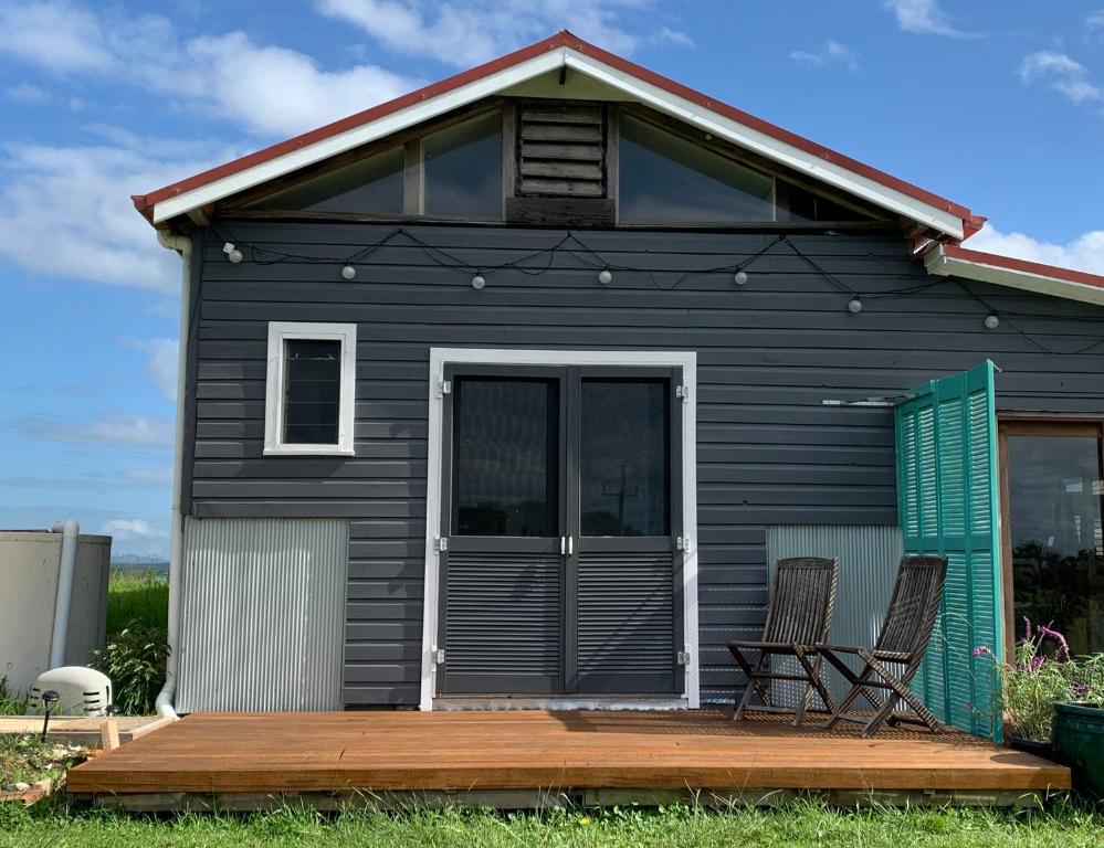 a black tiny house with two chairs on a deck at The Hay Shed in Mitchells Island