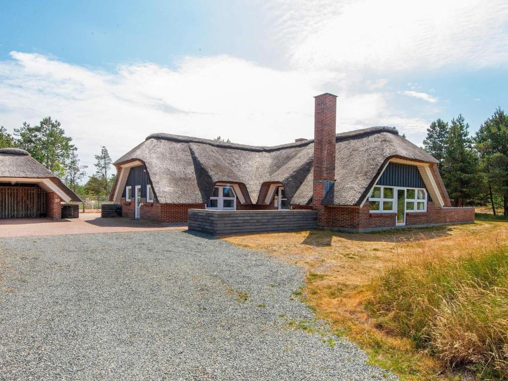 a house with a thatched roof and a driveway at 14 person holiday home in R m in Kongsmark