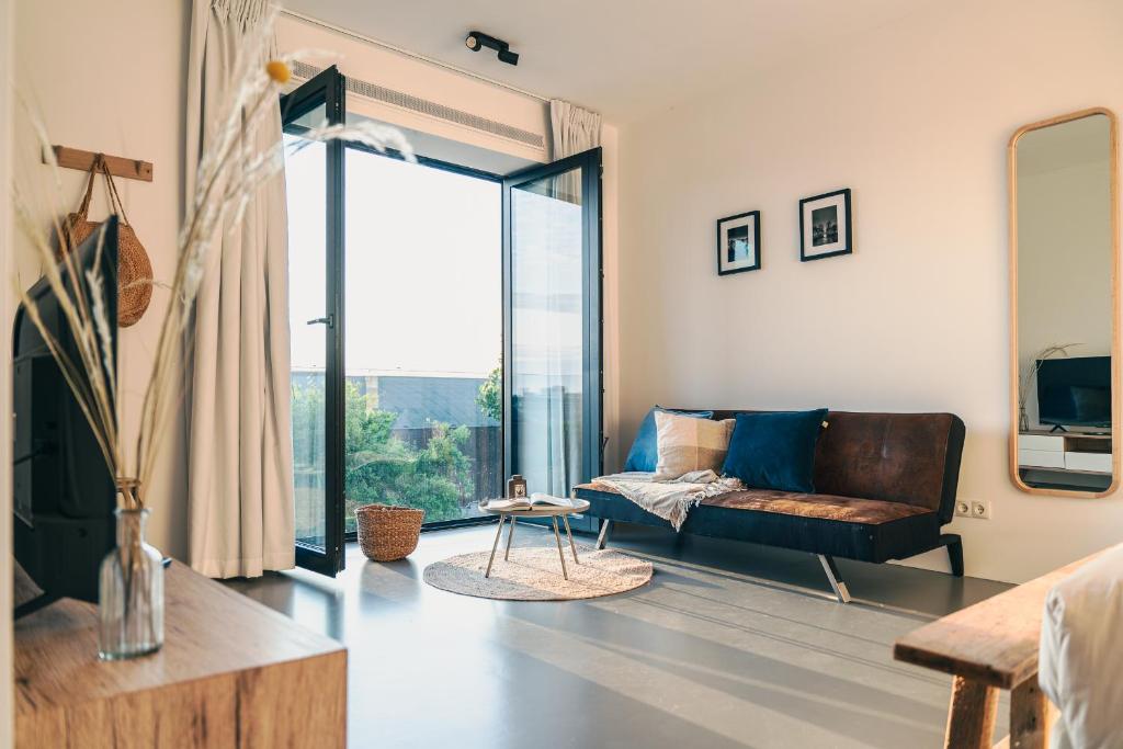 ein Wohnzimmer mit Couch und großem Fenster in der Unterkunft BNBNRD Stylish Boutique Apartment 45m2 w Panoramic Views - private entrance in Amsterdam