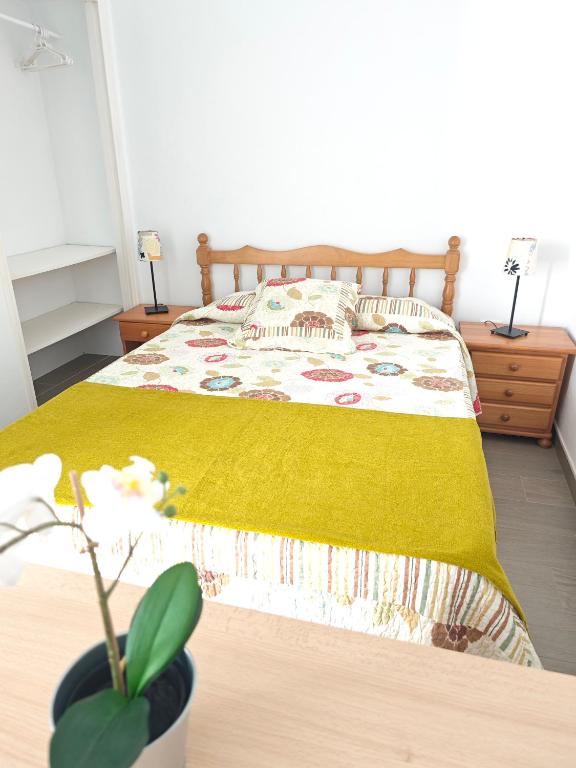 een slaapkamer met een bed met een gele deken bij Cozy Apartment in front of the Natural Pools in El Pris
