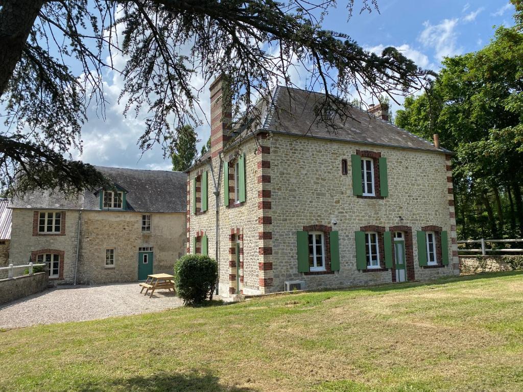 ein altes Backsteinhaus mit grünen Rollläden und einem Hof in der Unterkunft Le Moulin du Saon in Saon
