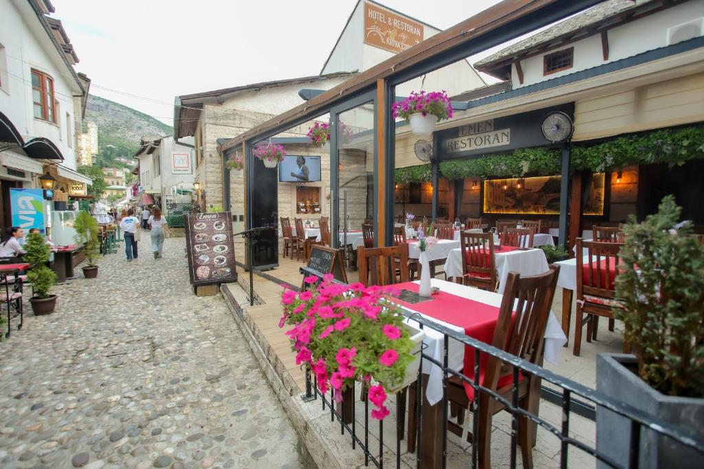 - un restaurant avec des tables, des chaises et des fleurs dans une rue dans l'établissement Hotel Emen, à Mostar