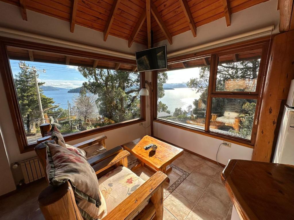 sala de estar con sofá, mesa y ventanas en Ruca Nehuen en San Carlos de Bariloche