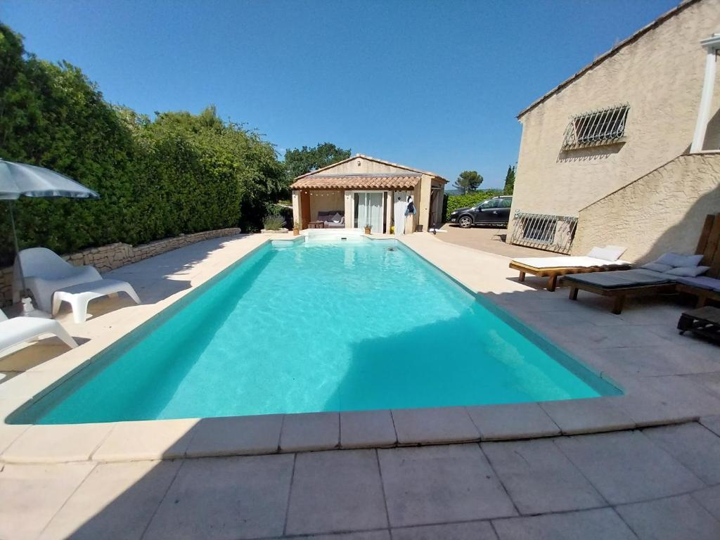 uma grande piscina azul ao lado de um edifício em Jolie maison provençale. em Saint-Estève-Janson
