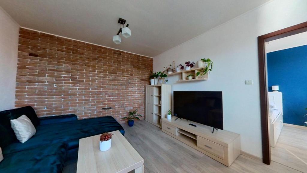 a living room with a blue couch and a brick wall at Air conditioned, 2 room Apartment, New City in Koliba