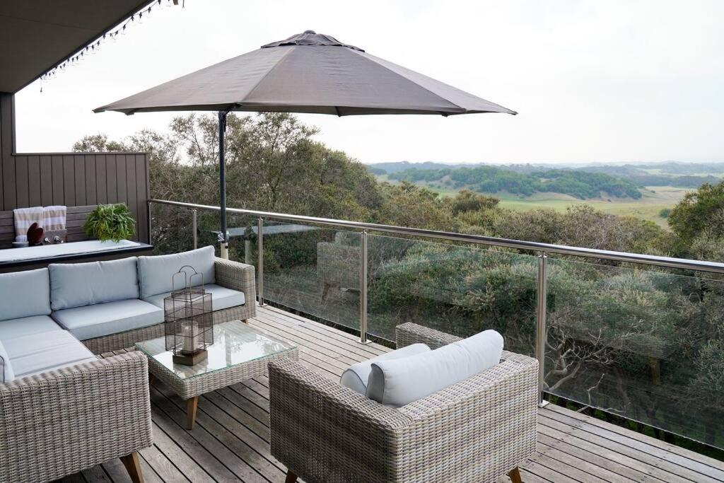 a patio with a couch and an umbrella on a deck at SaltBush in Saint Andrews Beach