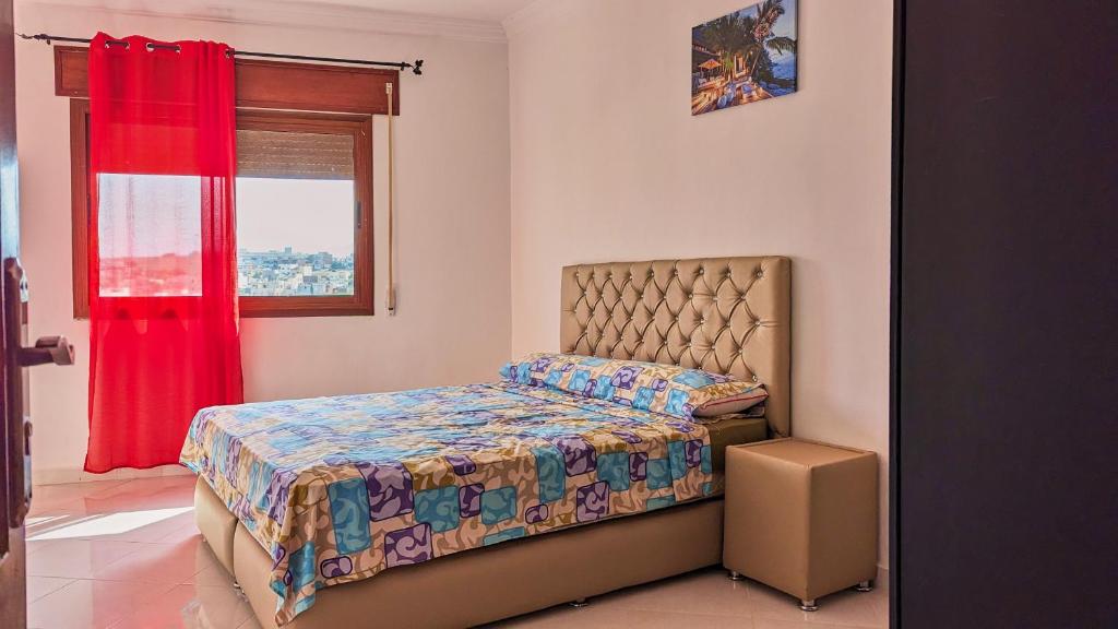 una camera da letto con un letto con una tenda rossa e una finestra di Oued Laou Apartment a Oued Laou