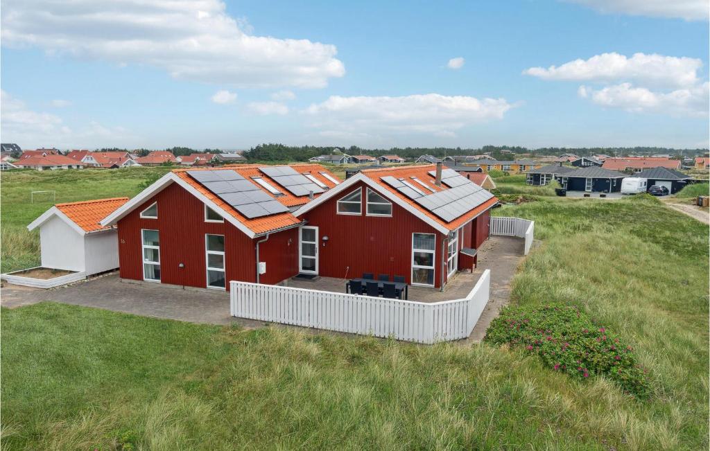 a red house with solar panels on it in a field at Cozy Home In Thisted With Wifi in Klitmøller