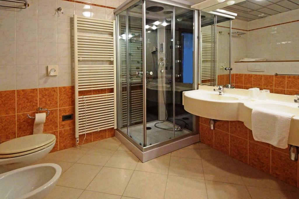 łazienka z 2 umywalkami, prysznicem i toaletą w obiekcie Park Hotel Zanzanù w mieście Tignale
