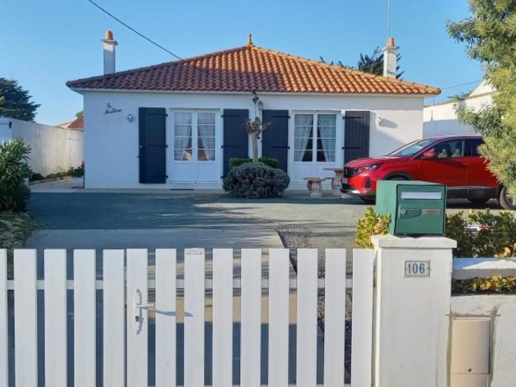 une maison blanche avec une voiture rouge garée devant elle dans l'établissement Maison spacieuse à Notre-Dame-de-Monts, 6 pers, 2 terrasses, proche plages et activités - FR-1-540-223, à Notre-Dame-de-Monts