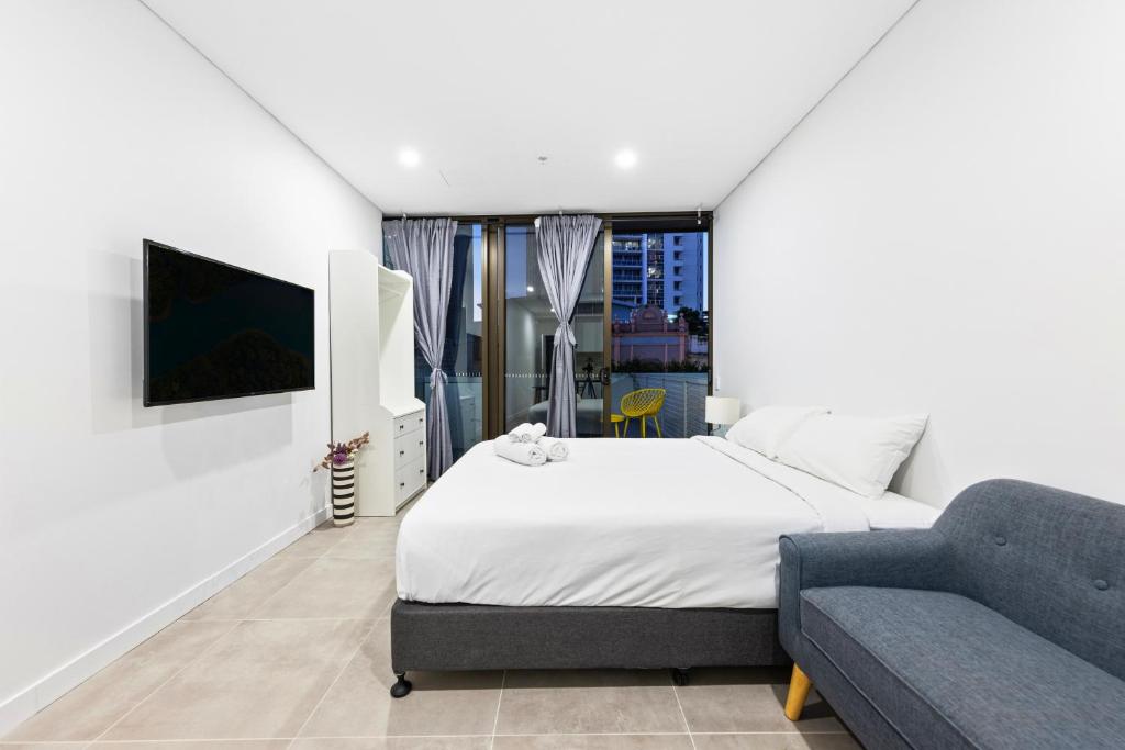 a white bedroom with a bed and a couch at Arthur's Hotel Bondi Junction in Sydney